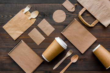 Set of recycle brown paper bag, disposable tableware cup, spoon, fork, notebook on wooden...