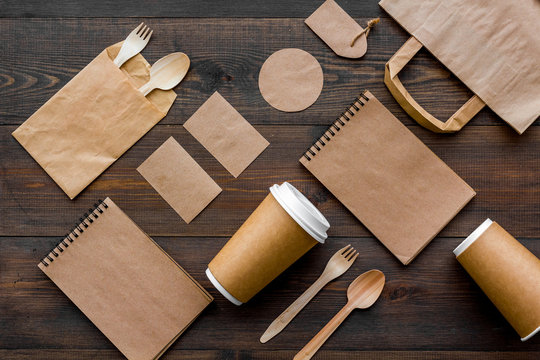 Set of recycle brown paper bag, disposable tableware cup, spoon, fork, notebook on wooden background top view pattern