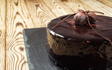 dark chocolate vegan cake with candies on wooden background, happy birthday concept