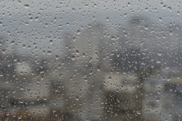 Rain drops on window, against blurry background of a town