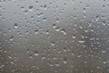 Rain drops on window, against blurry background of a town