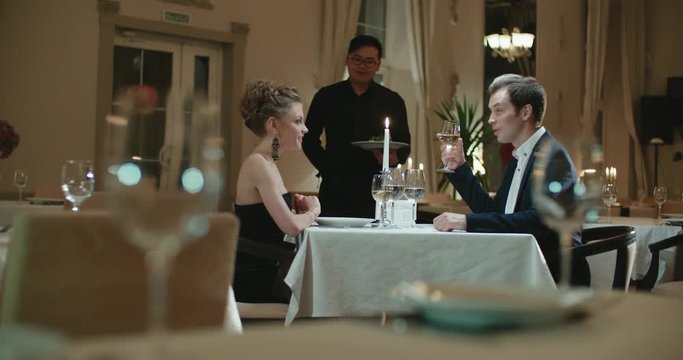 the young Asian waiter serving couple in restaurant for dinner