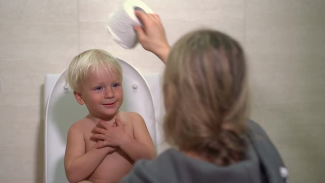 cute baby boy and mom playing with toilet paper