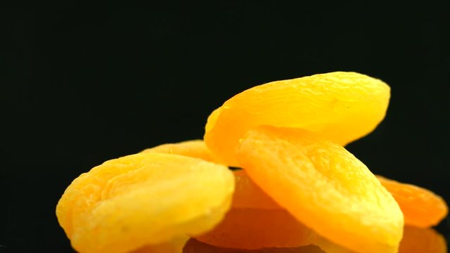 Dried apricots closeup. Sweet dried fruits on black background. Organic food. Rotation 360 degrees. 4K UHD video 3840x2160