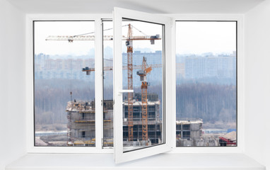 Loud construction site noise immission in opened one frame of pvc window, view through