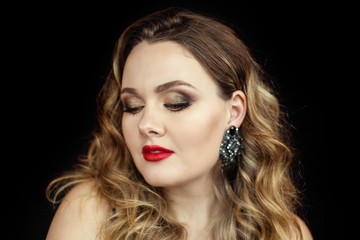 Portrait of a young beautiful woman with red lipstick on a black background. Makeup. Holidays. Beauty.