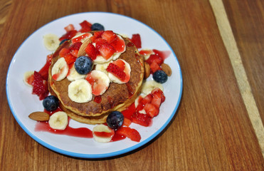 Stack of vegan pancakes with fresh berries and bananas