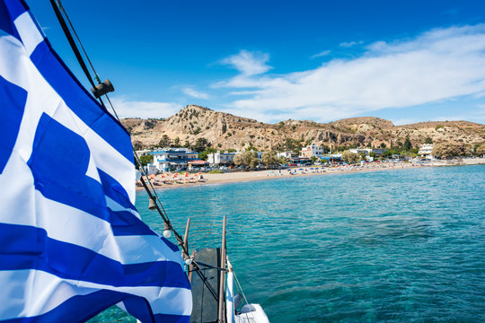 View of Greek flag on boat and Stegna beach behaind (RHODES, GREECE)