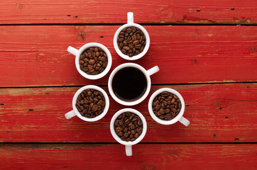 Coffee. Coffee cups and coffee beans on red wooden background.