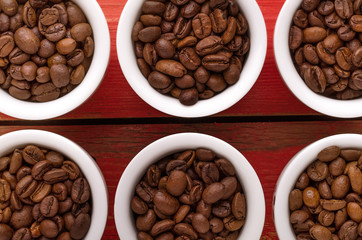 Coffee. Coffee cups and coffee beans on red wooden background.