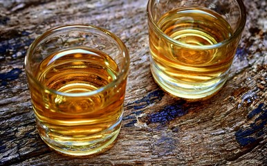 Alcohol,taste and drink concept-two glasses of whisky on an old wooden background.