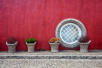 colored red house with a round window in summer in Portugal © Liliya Belaya