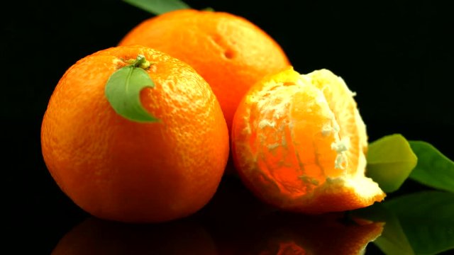 Ripe mandarines closeup. Organic juicy tangerines over black background. Rotation 360 degrees. 4K UHD video 3840x2160