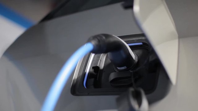 Color footage with a plug charging an electrical car.