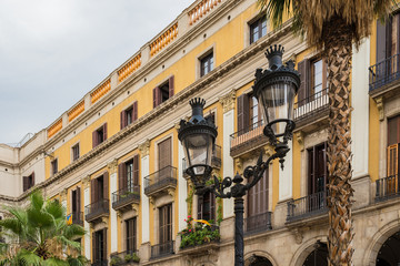 Street lamp in Royal square (Plaça Reial) and yellow building with balconies in Barcelona, Spain