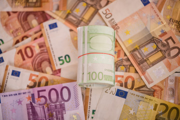 Obraz na płótnie Canvas rolled up one hundred euro notes bills on money background