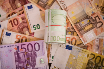 rolled up one hundred euro notes bills on money background