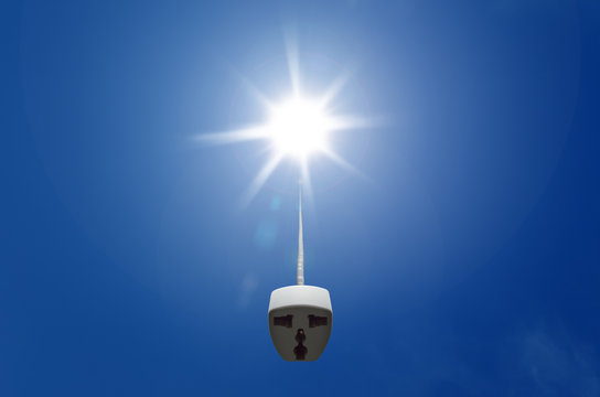 Female plug connected to the sun in blue sky, illustrating renewable energy