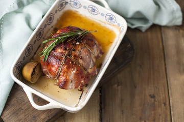 meat tied with rope, baked to a crust on a baking sheet with lime and rosemary, on a wooden table and towel