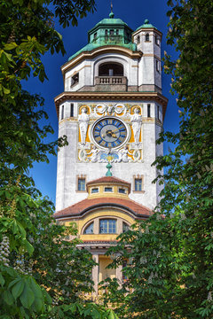 Turm mit Uhr des Müllerschen Volksbades in München umrahmt von Kastanien