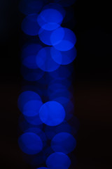 De-focused blue lights on dark background. Abstract optical composition