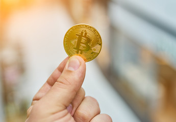 man's hand holding golden Bitcoin
