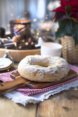 Christmas baked goods on a table near a window and a flower with red leaves, candles