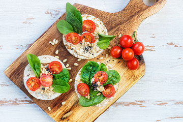 Healthy Snack from Rice Cakes with Hummus, Spinach and Tomatoes