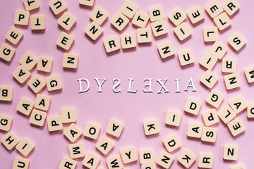 Dyslexia concept - alphabet tiles on a pink background