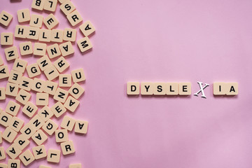 Dyslexia concept - alphabet tiles on a pink background