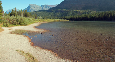 Irregular shoreline of Fishercap Lake on the Swiftcurrent hiking trail in the Many Glacier region of Glacier National Park during the 2017 fall fires in Montana United States