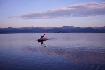 Lonely kayak on the water surface lake in evening time with cloudy and purple evening sunset