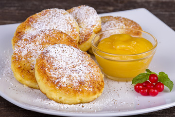 Cottage cheese pancakes, homemade syrniki with honey in white plate.