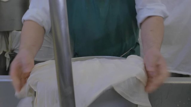 Man seals cheese into a barrel with cloth for processing