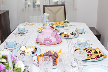 A festive table with cups of flowers and fruits. Delicious cake and cookies