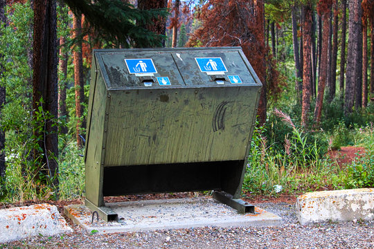 a bear proof garbage container along side a parking lot