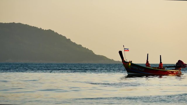 Life video The fishermen sailed through group of long-tail boats floating in the andaman sea with golden light of the Sun  before sunset in life and transportation concept.