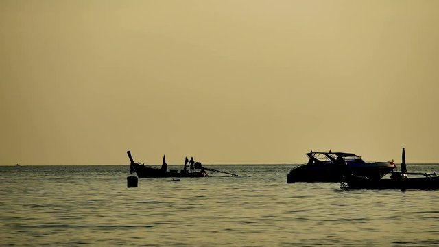 Travel video silhouette Long-tail boats sailing on the andaman  sea with golden light of the Sun  before sunset in travel or transportation concept.