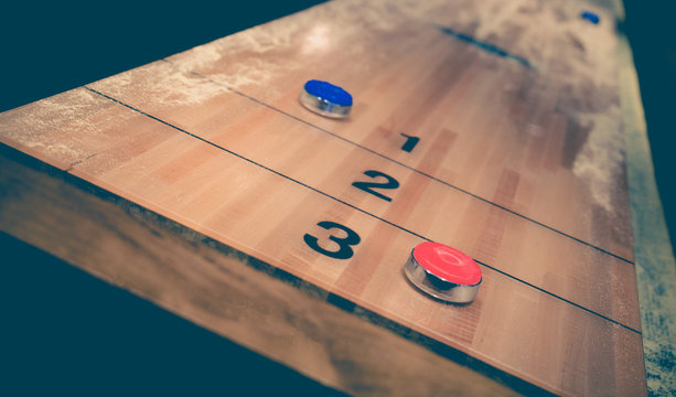 Vintage shuffle board game with red and blue disc on wooden shuffle table. Shuffleboard table game with selective focus.