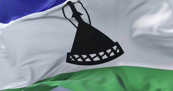 Flag of Lesotho waving at wind with blue sky in slow, loop