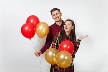 Fototapeta na wymiar Beautiful caucasian young happy smiling couple in love. Woman and man in plaid checkered clothes with red, yellow balloons, celebrating birthday, on white background isolated. Holiday, party concept.