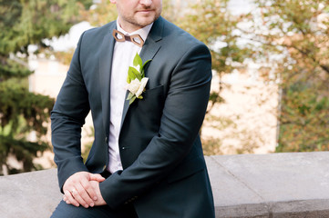 A close-up of the chin of a bearded stylish groom. To correct a butterfly with a buttonhole in the...