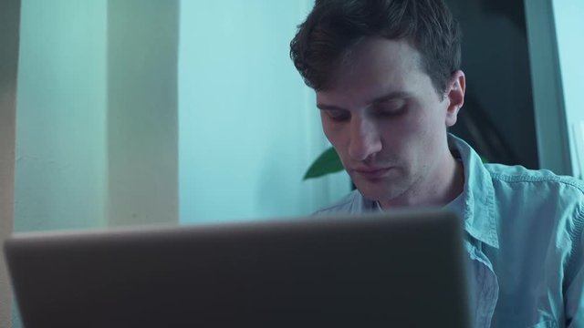 Man using notebook computer sitting near window