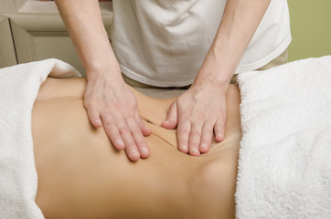 Relaxing professional massage on the female abdomen in the salon.