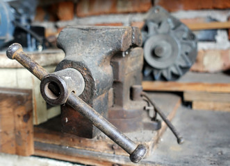 Old vise in the workshop. The hand tool is on the table      