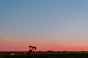 Fototapeta premium At sunset, oil pumps pump oil on a black field.