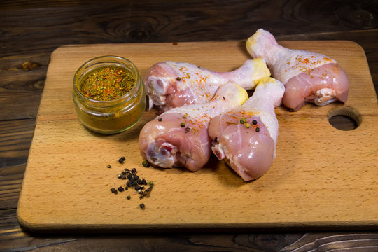 Raw chicken legs with spices on wooden table