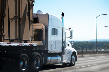 Naklejka na ściany i meble Big rig semi truck with flat bed semi trailer transport commercial cargo on the road