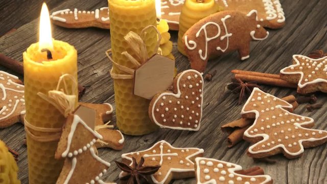 Christmas homemade gingerbread cookies on wooden desk. Yellow scented candles made from natural beeswax.
