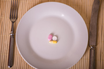 loose pills tablets antibiotics pain killer on a white plate 